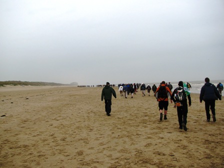 Die lange Marathonschlange kämpft sich durch den Sand